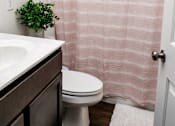 Thumbnail 60 of 60 - A white toilet sits under a pink shower curtain in a bathroom.