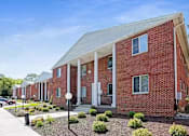 Thumbnail 8 of 27 - A red brick building with a white roof and a front porch.