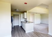 Thumbnail 46 of 48 - A kitchen with white cabinets and a countertop is visible from the living room.