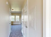 Thumbnail 48 of 48 - A long hallway with white walls and a carpeted floor.