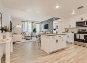 Thumbnail 36 of 69 - a kitchen and living room with white walls and wood flooring