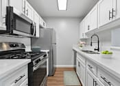 Thumbnail 12 of 30 - A modern kitchen with white cabinets and stainless steel appliances.