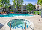 Thumbnail 13 of 37 - Resort-style swimming pool and serene spa at Caifornia Place in gated pool area surrounded by lush greenery and blue skies for a beautiful and relaxing poolside experience. With plenty of seating including dining tables and chaise lounges