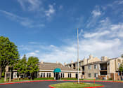 Thumbnail 3 of 37 - Entrance to leasing office at California Place apartments surrounded by lush greenery and blue skies