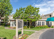 Thumbnail 2 of 37 - driveway leading into California Place apartments surrounded by lush greenery