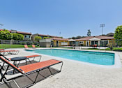 Thumbnail 6 of 30 - Luxurious swimming pool at Azusa Gardens surrounded by chaise loungers and lush greenery