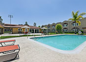 Thumbnail 7 of 30 - Luxurious swimming pool at Azusa Gardens surrounded by chaise loungers and lush greenery