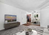Thumbnail 20 of 31 - Spacious living room in 2 Bed 1 Bath Bent Tree apartment home with carpeted flooring and open concept layout leading to dining nook and kitchen area. Dining nook and kitchen have plank wood-style flooring.