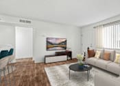 Thumbnail 25 of 31 - Living Room in 2 Bed 2 Bath Bent Tree Apartment with Large Windows allowing for gorgeous natural lighting, wood plank-style flooring, and view into dining nook & kitchen complete with bar top seating
