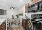Thumbnail 14 of 31 - Kitchen in 2 Bedroom 1 Bath Option B Bent Tree Apartment with wood plank-style flooring, dark wood cabinets, black appliances, and modern marbled countertop.