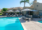 Thumbnail 19 of 36 - a swimming pool with tables and umbrellas in front of leasing office