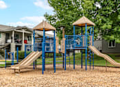 Thumbnail 8 of 31 - Play park at Bent Tree apartments with large play structure equipped with slides and climbing equipment. Surrounded by grass and cozy park-like landscaping