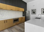 Thumbnail 10 of 69 - a kitchen with wooden cabinets and a white counter top and a sink at The Venue at Orange Apartments, Redlands, CA