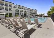 Thumbnail 22 of 69 - a large pool with lounge chairs in front of a building at The Venue at Orange Apartments, Redlands, 92373