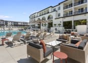 Thumbnail 19 of 69 - a person sitting on a lounge chair next to a pool at The Venue at Orange Apartments, Redlands, CA