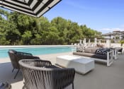 Thumbnail 21 of 69 - a poolside patio with chairs and tables and a pool at The Venue at Orange Apartments, Redlands
