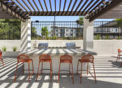 Thumbnail 23 of 69 - a patio with a bar with chairs and a table at The Venue at Orange Apartments, California, 92373