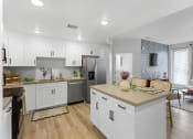 Thumbnail 40 of 69 - an open kitchen and living room with white cabinets and stainless steel appliances