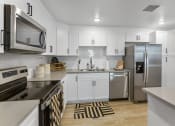 Thumbnail 47 of 69 - an open kitchen with white cabinets and stainless steel appliances
