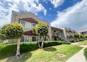 Thumbnail 10 of 30 - Exterior of Azusa Gardens Apartment Homes with grass-lined walkways and plenty of lush greenery