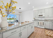 Thumbnail 25 of 38 - Modern kitchen with granite countertops and white cabinets at Altitude Apartments, Moreno Valley, CA 92553