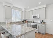 Thumbnail 15 of 38 - Kitchen with island seating and granite counters at Altitude Apartments, Moreno Valley