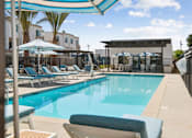 Thumbnail 8 of 38 - Swimming pool with striped umbrellas and sun loungers at Altitude Apartments, Moreno Valley, CA