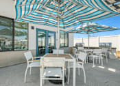 Thumbnail 11 of 38 - Patio area with grills and striped umbrellas at Altitude Apartments, California, 92553