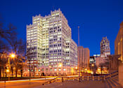 Thumbnail 17 of 17 - A large building with many windows is lit up at night.