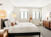 Thumbnail 10 of 17 - A bedroom with a large bed, a dresser, and a mirror.