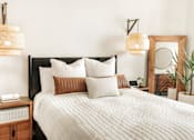 Thumbnail 11 of 17 - A bed with a white comforter and pillows is flanked by two hanging lamps.