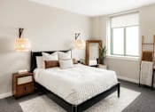Thumbnail 9 of 17 - A bedroom with a large bed and a wooden nightstand.