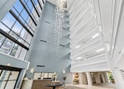 Thumbnail 27 of 37 - A modern interior with a chandelier and a view of the sky through the windows at Hampton Apartments, Clearwater, Florida