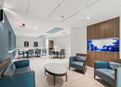Thumbnail 31 of 37 - A room with blue chairs and a television displaying blue flowers at Hampton Apartments, Clearwater, FL, 33759