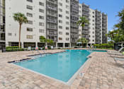 Thumbnail 10 of 37 - A swimming pool in front of a tall building with palm trees at Hampton Apartments, Florida, 33759