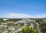 Thumbnail 17 of 37 - A modern building with a curved roof is surrounded by trees and open land at Hampton Apartments, Florida, 33759
