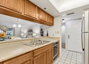 Thumbnail 22 of 37 - A kitchen with wooden cabinets and a black fridge at Hampton Apartments, Florida