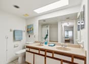 Thumbnail 33 of 37 - A bathroom with a toilet, sink, and mirror at Hampton Apartments, Clearwater 33759