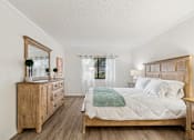 Thumbnail 24 of 37 - A bedroom with a large bed, a dresser, and a mirror at Hampton Apartments, Clearwater, FL, 33759
