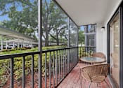 Thumbnail 4 of 37 - A balcony with a table and chairs overlooking a parking lot. at Hampton Apartments, Clearwater 33759