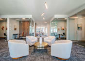 Thumbnail 22 of 28 - A spacious office lounge with white chairs and a glass table.