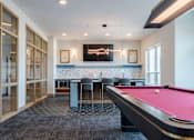 Thumbnail 13 of 28 - A pool table is in the middle of a room with a bar and a television.