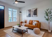 Thumbnail 28 of 28 - A living room with a brown couch, a coffee table, and a ceiling fan.