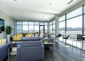 Thumbnail 37 of 46 - a living room with blue couches and chairs and a large window with a view at 1400 Russell Apartments, Saint Louis, Missouri