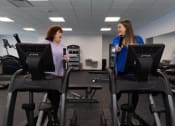 Thumbnail 10 of 33 - two women on exercise machines in a gym at The Residences at Tesson Ridge, Saint Louis, MO, 63128