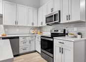 Thumbnail 22 of 33 - a kitchen with white cabinets and black appliances at The Residences at Tesson Ridge, Saint Louis, 63128