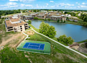Thumbnail 107 of 112 - A tennis court is located on a grassy area next to a lake. at The Residences at Tesson Ridge Apartments, Saint Louis, MO, 63128