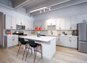 Thumbnail 34 of 112 - A kitchen with white cabinets and a white island with two black chairs. at The Residences at Tesson Ridge Apartments, Saint Louis