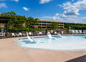 Thumbnail 75 of 112 - A large outdoor swimming pool with a water slide and lounge chairs. at The Residences at Tesson Ridge Apartments, Saint Louis, Missouri