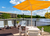 Thumbnail 82 of 112 - A yellow umbrella is on a patio table with chairs. at The Residences at Tesson Ridge Apartments, Saint Louis, Missouri